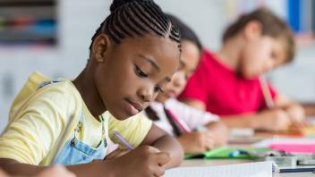 3 elementary students writing in class